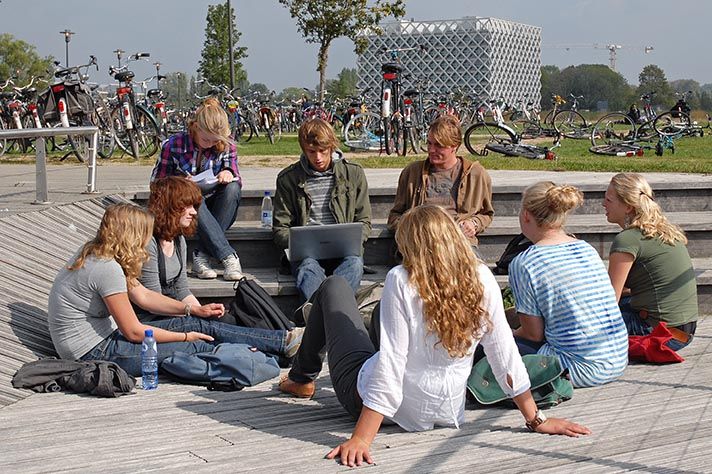 Studenten buiten voor onderwijsgebouw Forum. Atlas op de achtergrond.